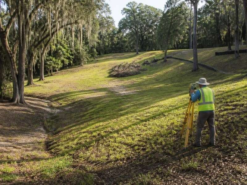 Land surveyor documenting elevation changes on a sloped property in Savannah, GA.